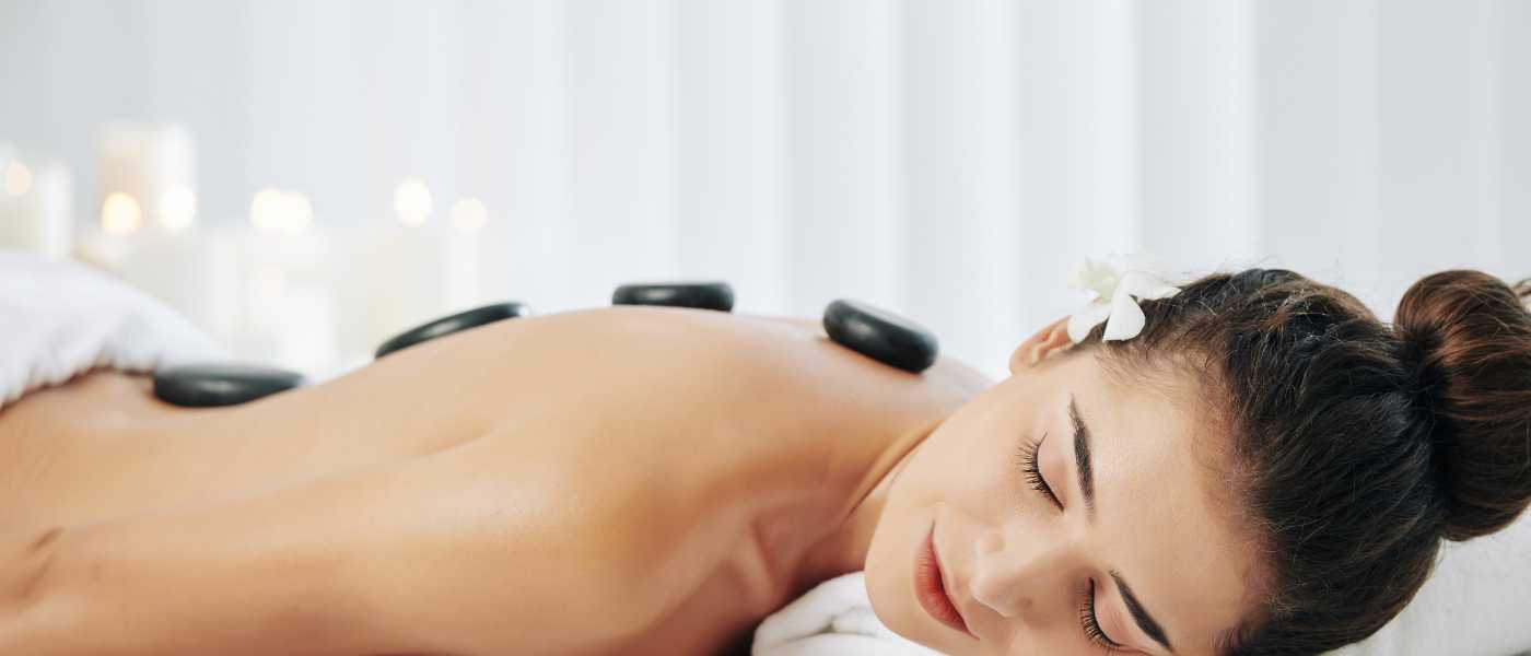 Woman lying on massage table with hot stones placed on her back